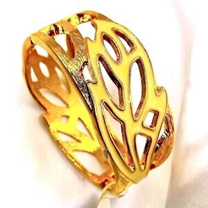 wide gold-tone cuff bracelet with a cream enamel fill in an abstract